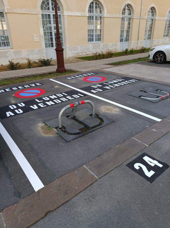 Réalisation de place de stationnement avec lettrage sur support en enduit noir + logo interdit de stationner 